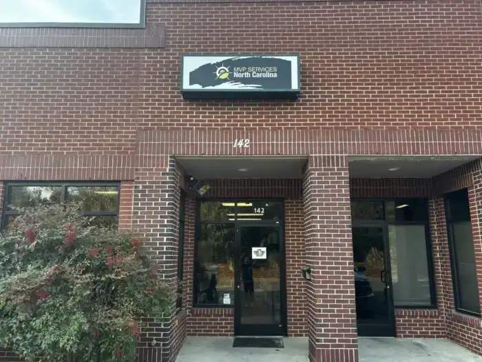 A brick building with a sign above the door reading "MVP Services North Carolina" and the street number 142 displayed above the entrance.