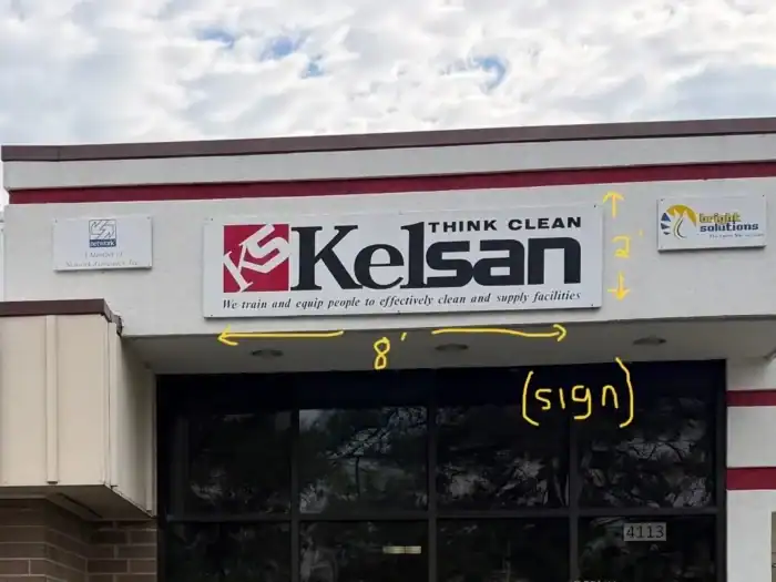 The exterior of a Kelsan building with a sign reading "Kelsan THINK CLEAN," annotated with measurements and labeled arrows indicating the sign's dimensions.
