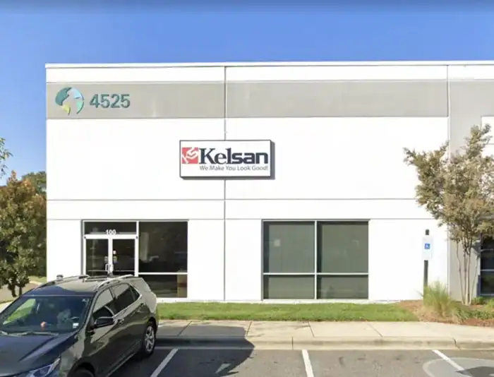 A white office building with a sign reading "Kelsan We Make You Look Good," address number 4525, and a parked car in front.